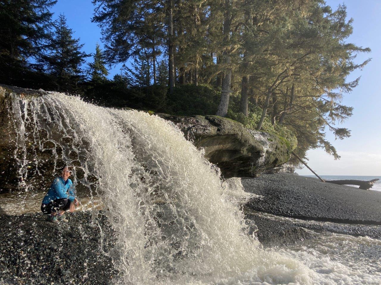Woman crouching behind waterfall