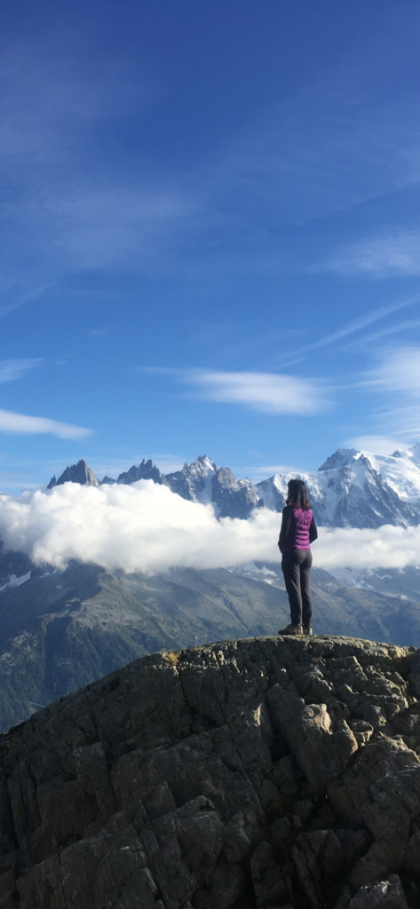 Woman standing on hill looking at Tour du Mont Blanc montains