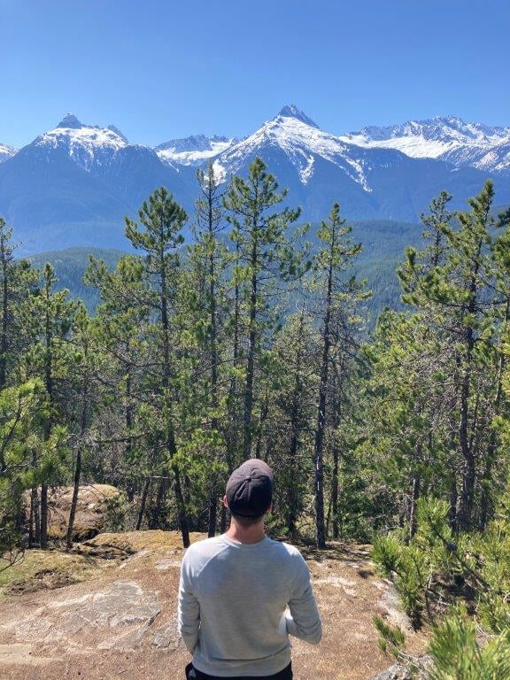 Man looking at snow covered Tantalus Mountain range on one of the best Squamish hikes