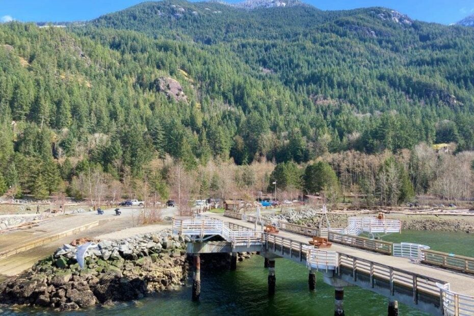 Dock and parking area of the Porteau Cove Provincial Park with trees and a mountain behind