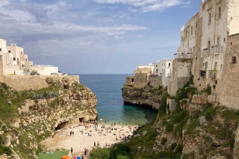 Small Puglia beach between cliffs lined with buildings