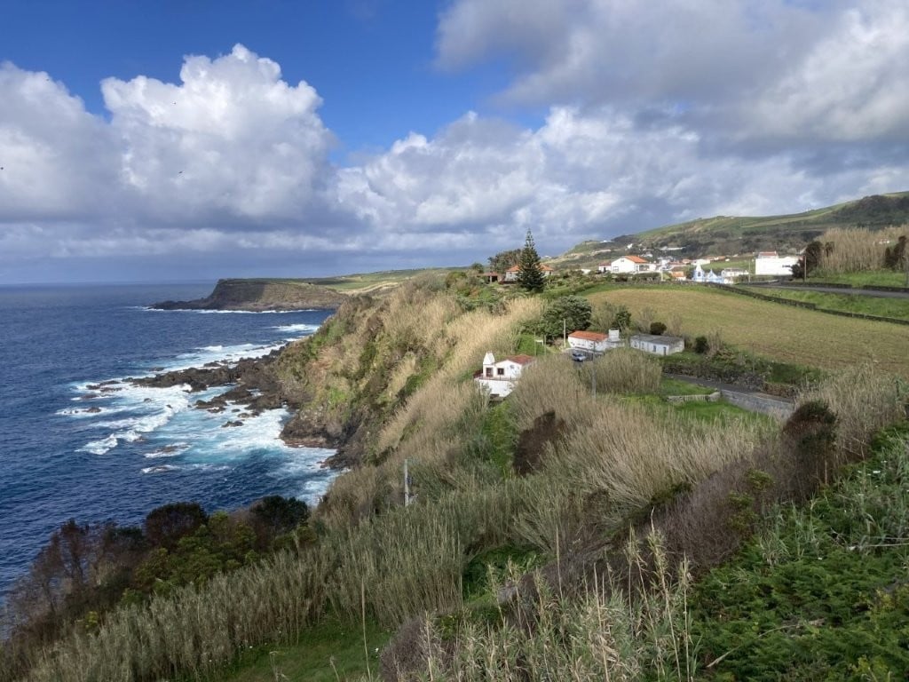Grassy coastline with a few building and some low clouds