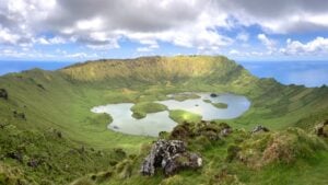 Lush green caldera on Corvo Azores with lakes at the bottom and the ocean in the background