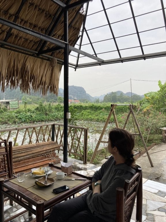 Woman having breakfast on an outdoor terrace overlooking a rice field