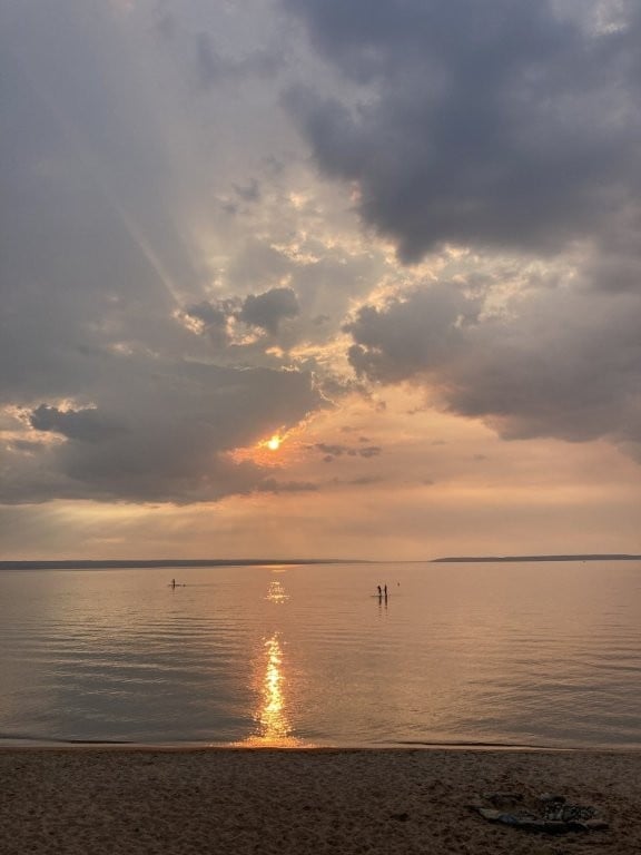 Sun setting through clouds over a lake