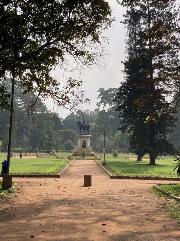 Dirt path leading through a park to an ancient statue