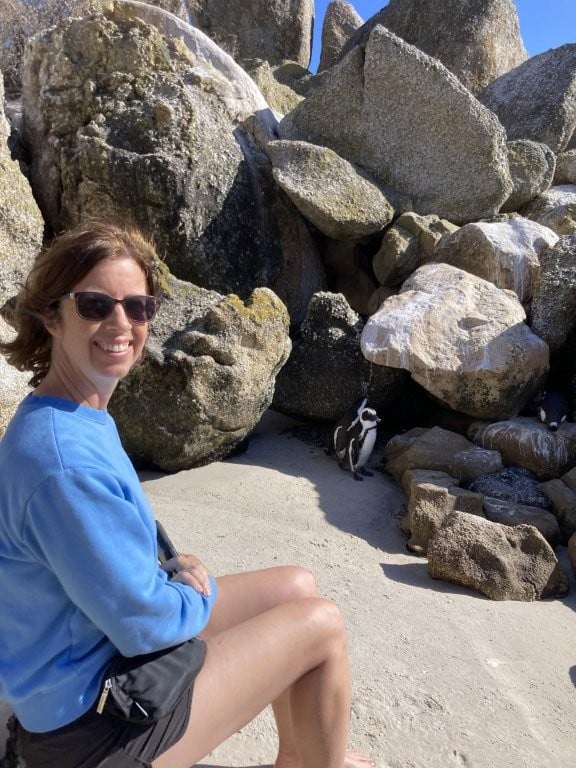 Woman sitting on a rock next to penguins