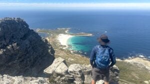 Man standing on a rocky ledge overlooking the South African coast