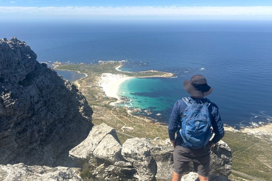 Man standing on a rocky ledge overlooking the South African coast