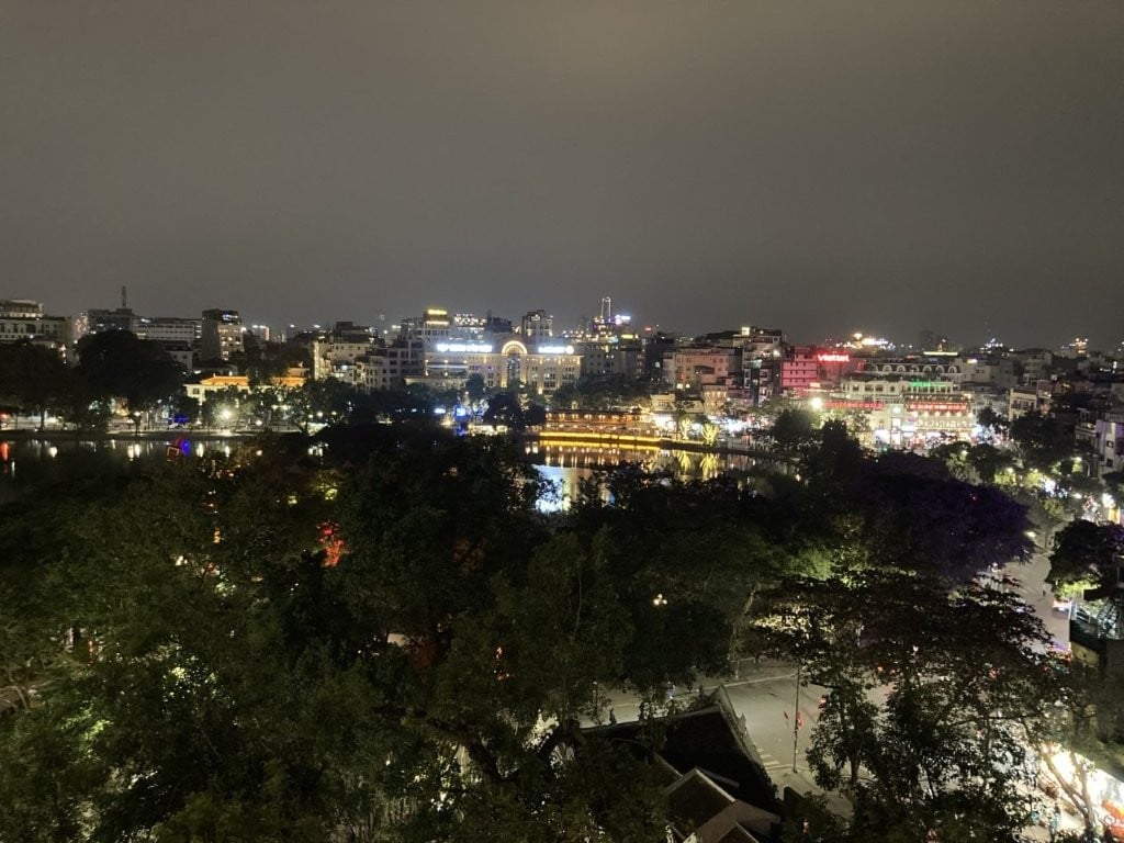 Hanoi lake at night surrounded by lit up buildings