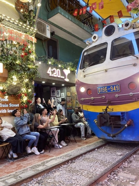 Train passing close by restaurant patrons having drinks