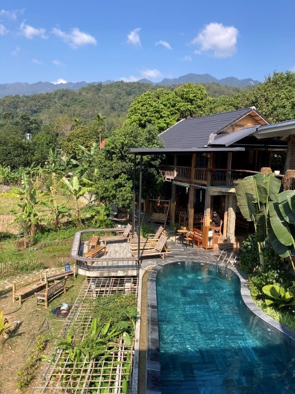 Small hotel with blue pool surrounded by jungle
