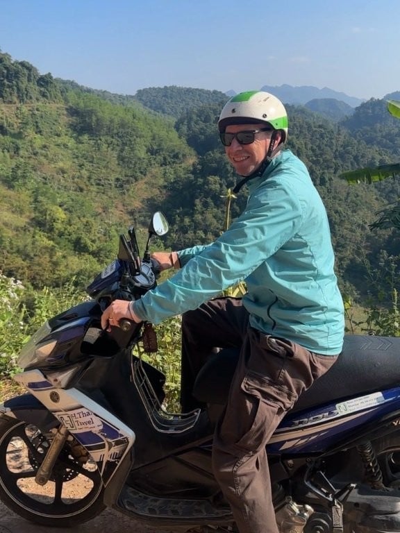 Man riding a scooter in front of a green valley