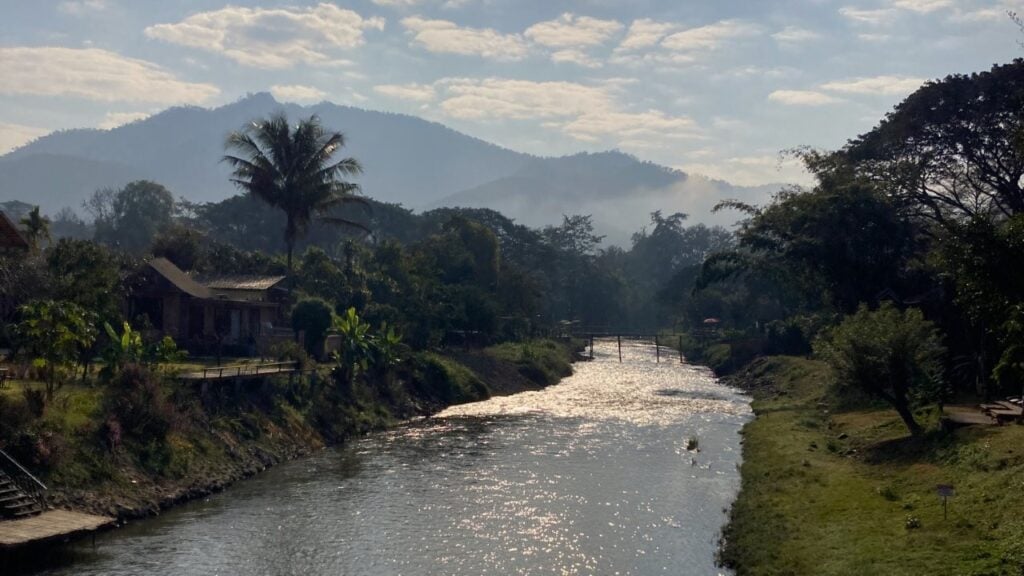 Small creek lined by trees with hills in distance
