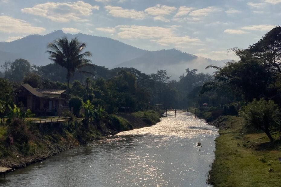 Small creek lined by trees with hills in distance