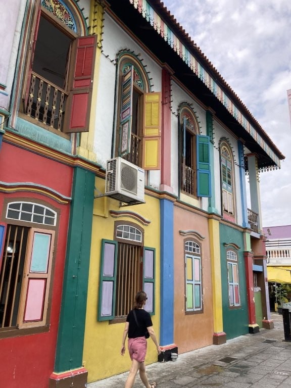 Woman walking next to a very colourful building