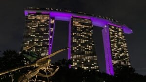 Marina Bay Sands hotel in purple lights at night with dragonfly statue in foreground