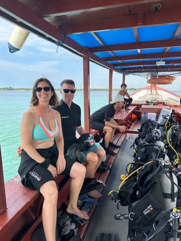 Couple in wetsuits on boat getting ready to scuba dive