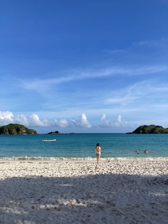 Woman crossing the beach toward the ocean
