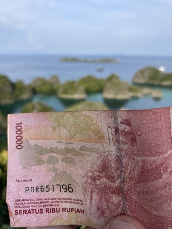 A 100,000-rupiah note in front of the islands of Piaynemo