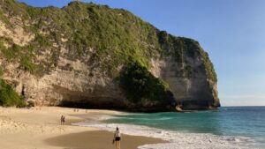 Woman walking on beach backed by cliffs