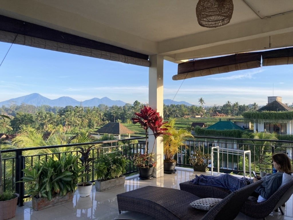 Woman lounging on terrace overlooking rice fields and volcanoes