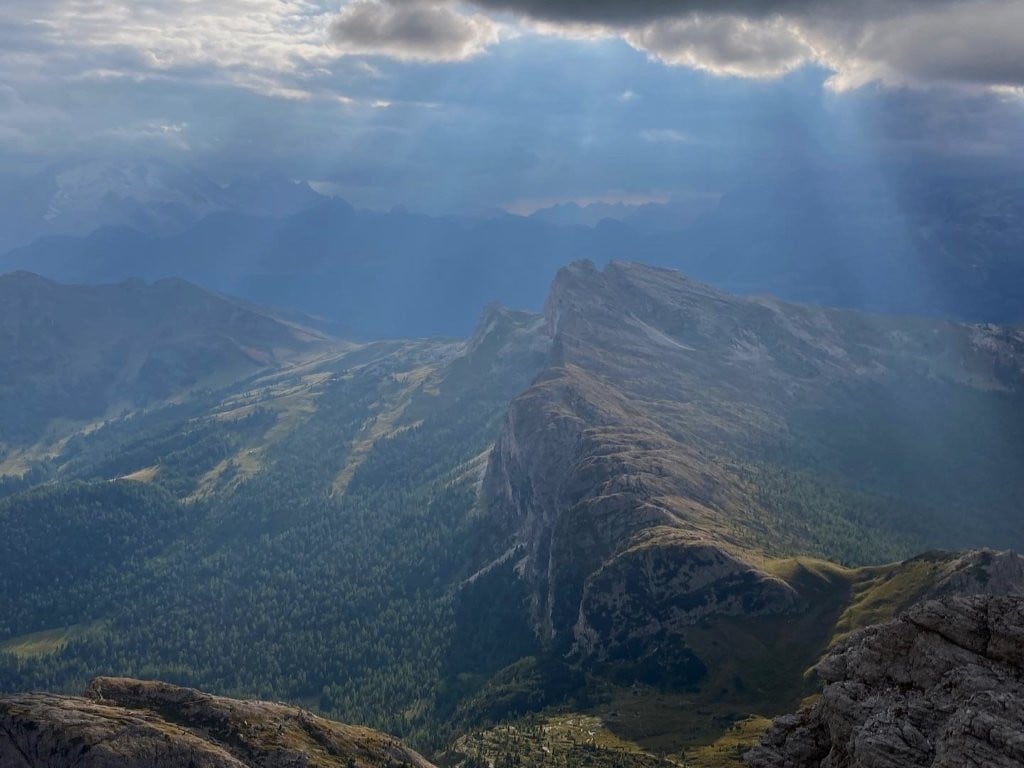 Sunbeams coming through clouds over grassy mountain range