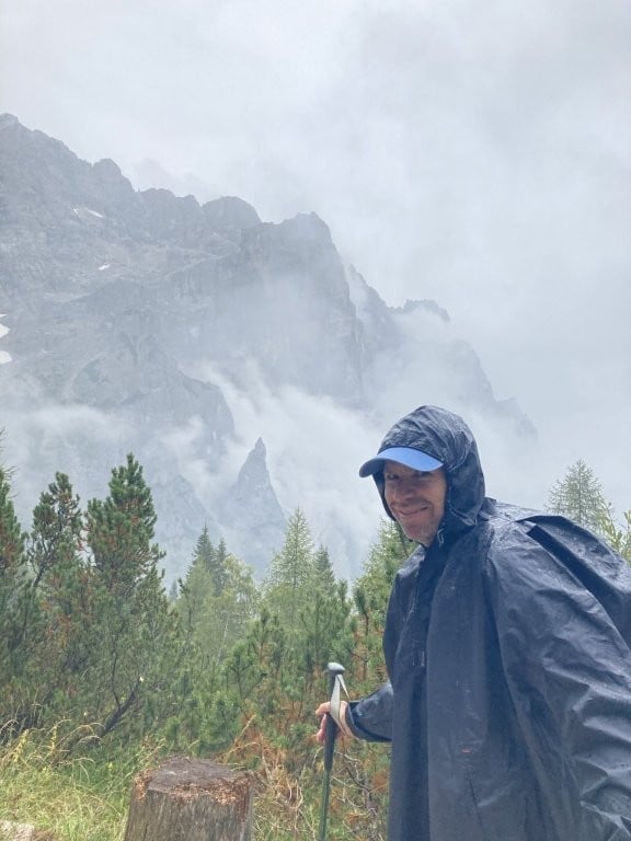 Hiker in a rain poncho with cloudy mountains