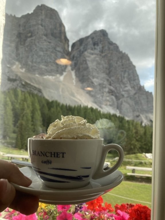 Cup of hot chocolate with whipped cream in front of mountains