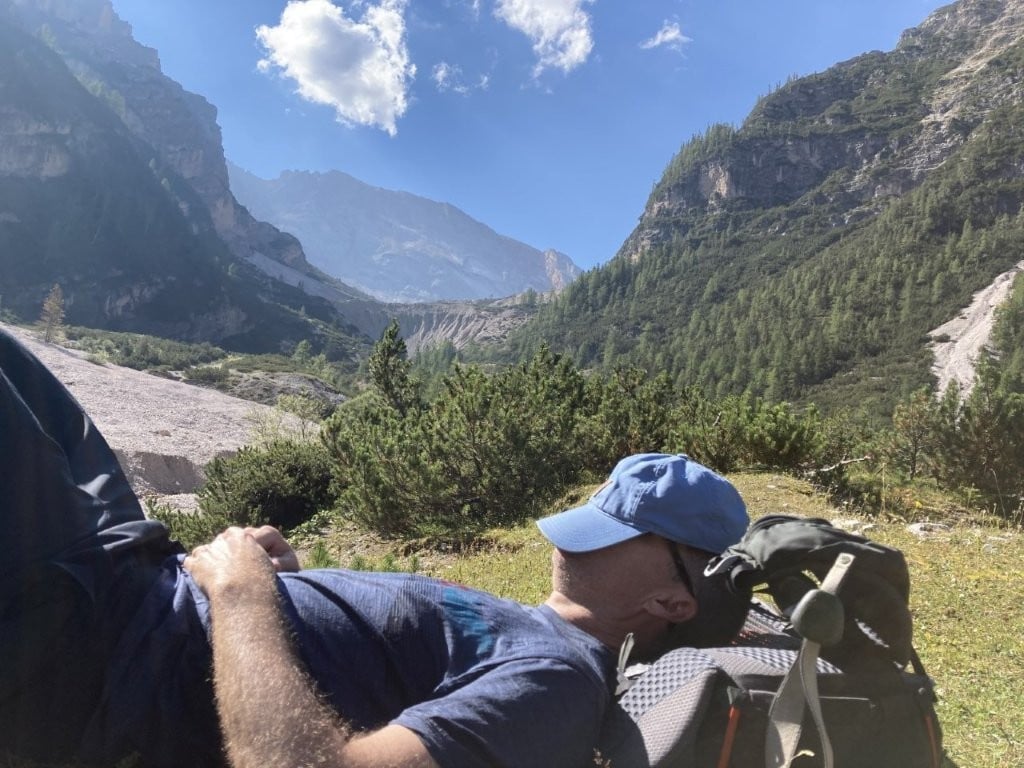 Hiker resting on ground with hat over face