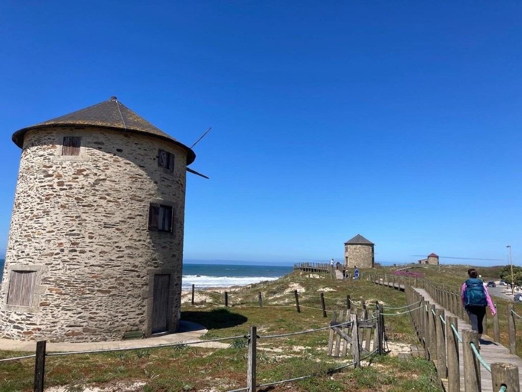 Hiker on beach boardwalk next to a stone granary