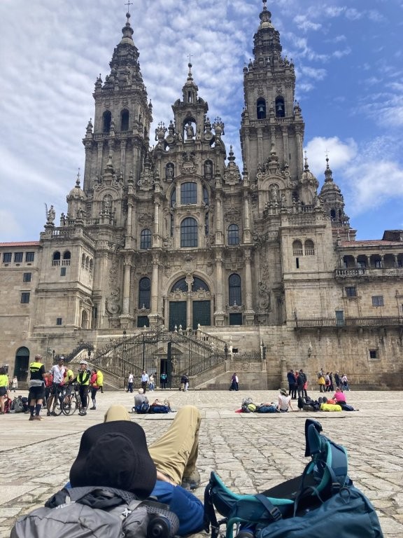 Hiker resting on backpack in front of the Santiago de Compostela Cathedral