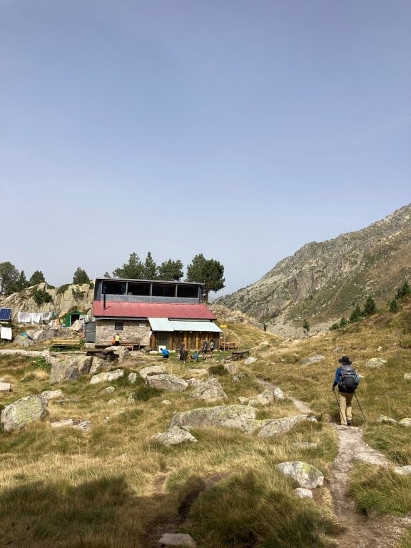 Hiker approaching a mountain hut on the Carros de Foc trek