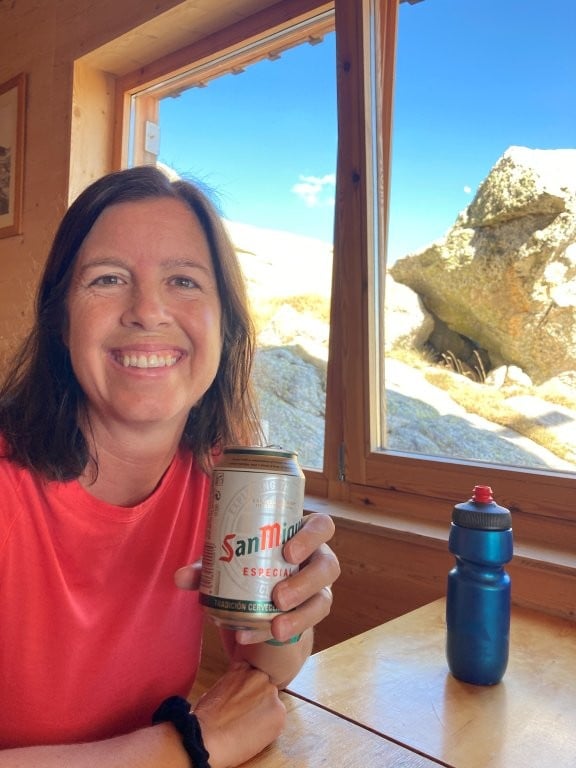 Woman holding up a beer with mountains out the window