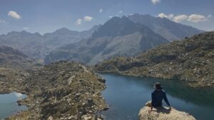 Man on rock overlooking lake and mountains