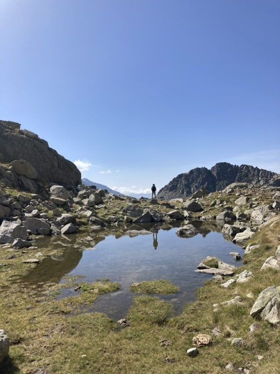 Hiker reflected in a rocky mountain lake