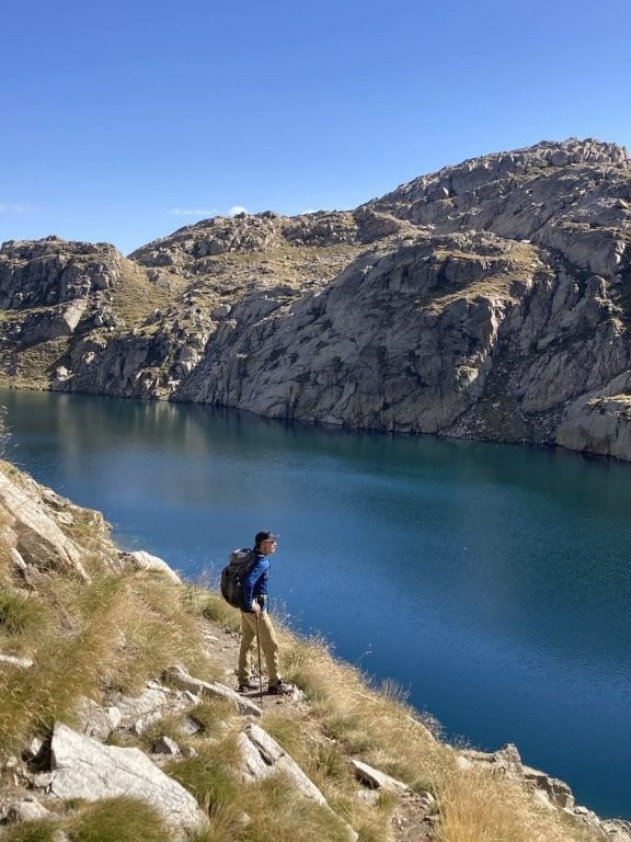 Hiker on trail overlooking mountain lake