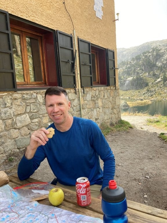 Man having lunch next to a hut on the Carros de Foc trek