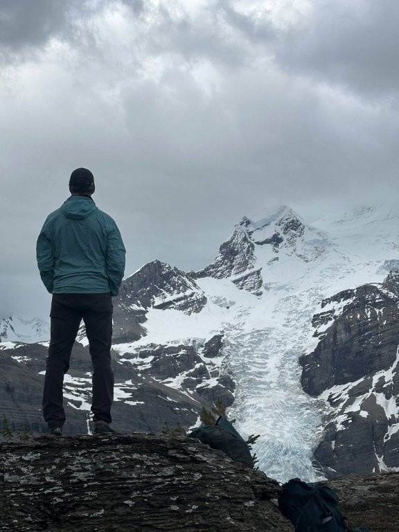 Man on rock with mountain glacier in background