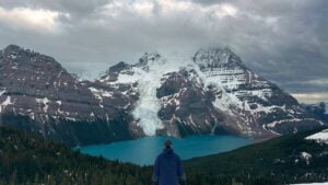Man on hill overlooking lake and mountains