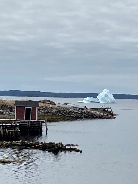 Small fishing shack with iceberg in the distance