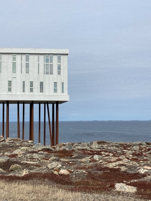 Large white hotel on stilts overlooking the ocean