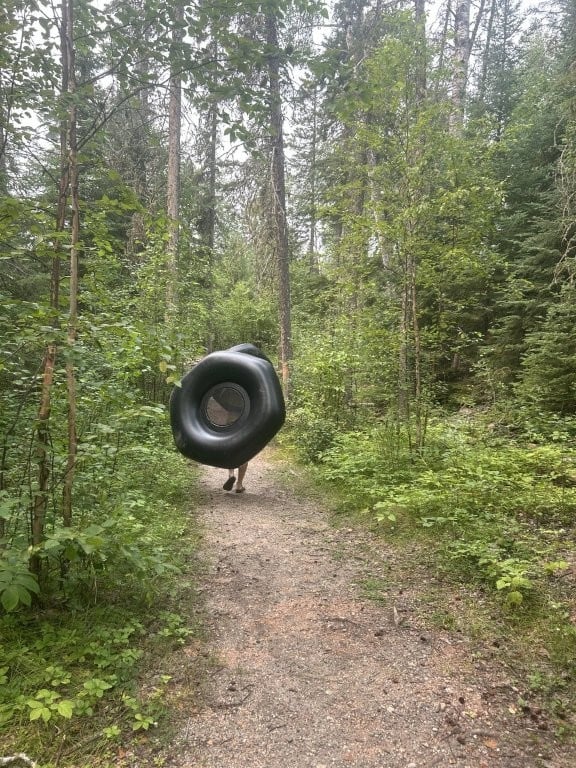 Person hauling a rubber tube through the bushes