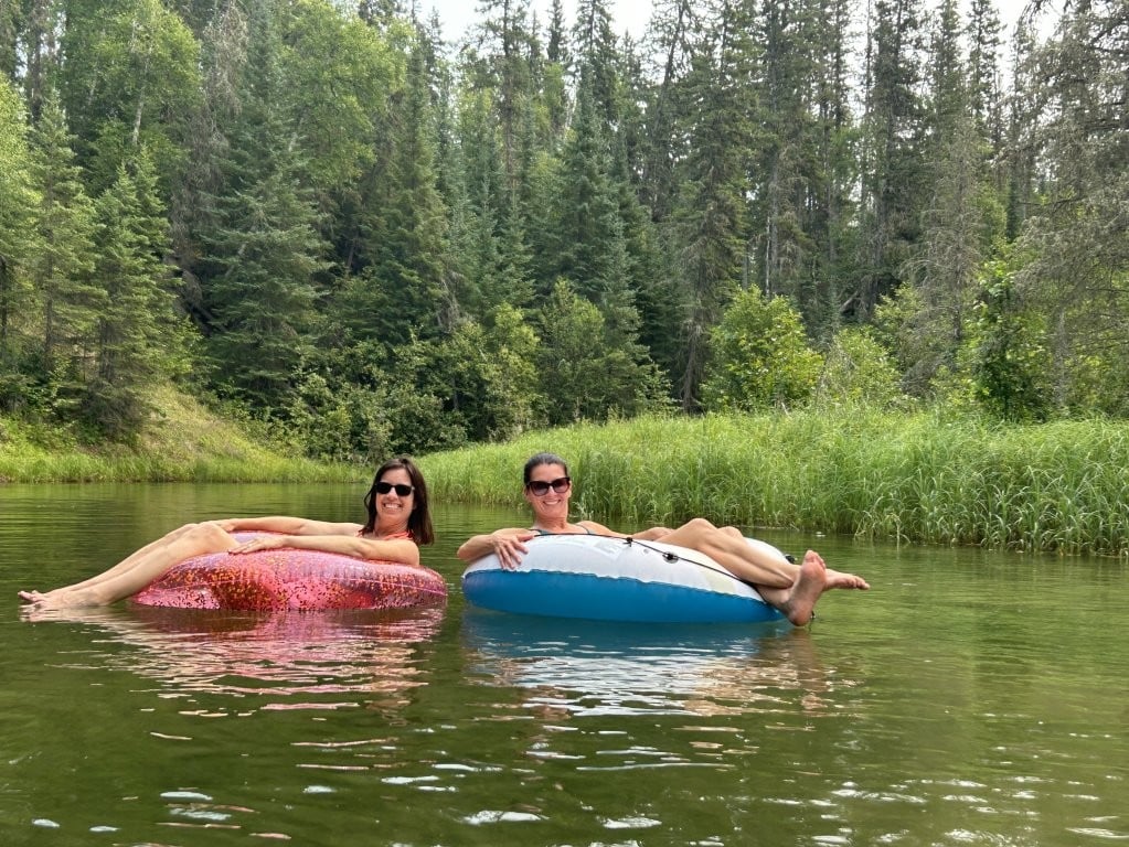 Two women floating on Kingsmere River in colourful tubes