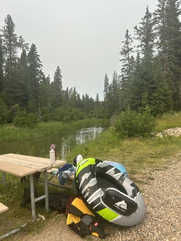 Tubes and gear next to a picnic table beside the river