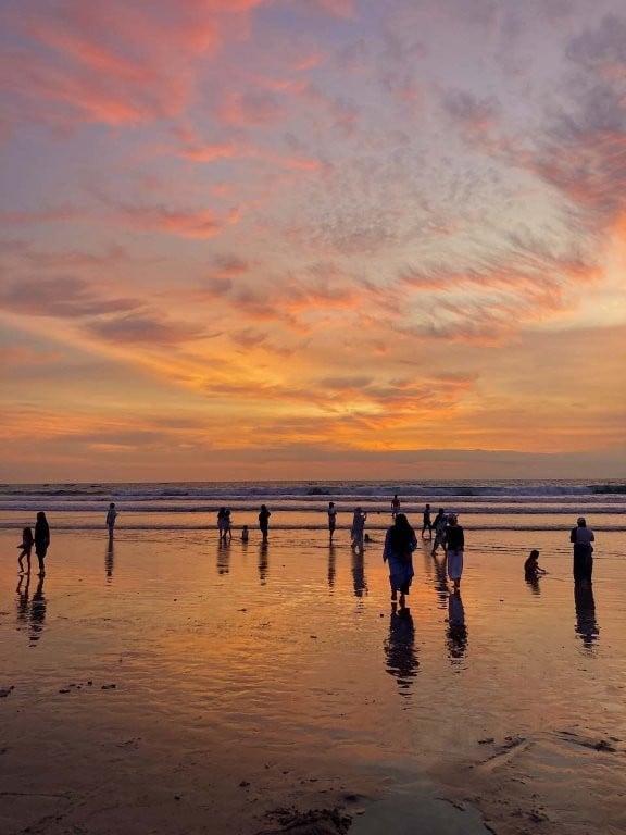 People on low tide beach at sunset