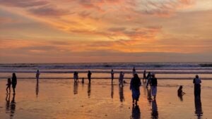 People on a long beach at sunset