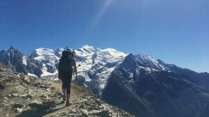 Hiker reaching the summit with mountains in background