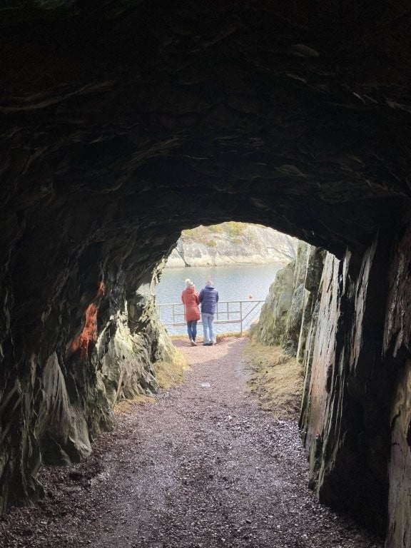 Couple standing on shore at the end of a long tunnel