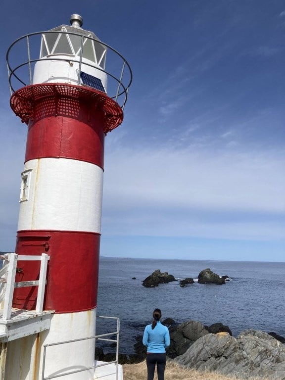 Woman next to a red and white lighthouse